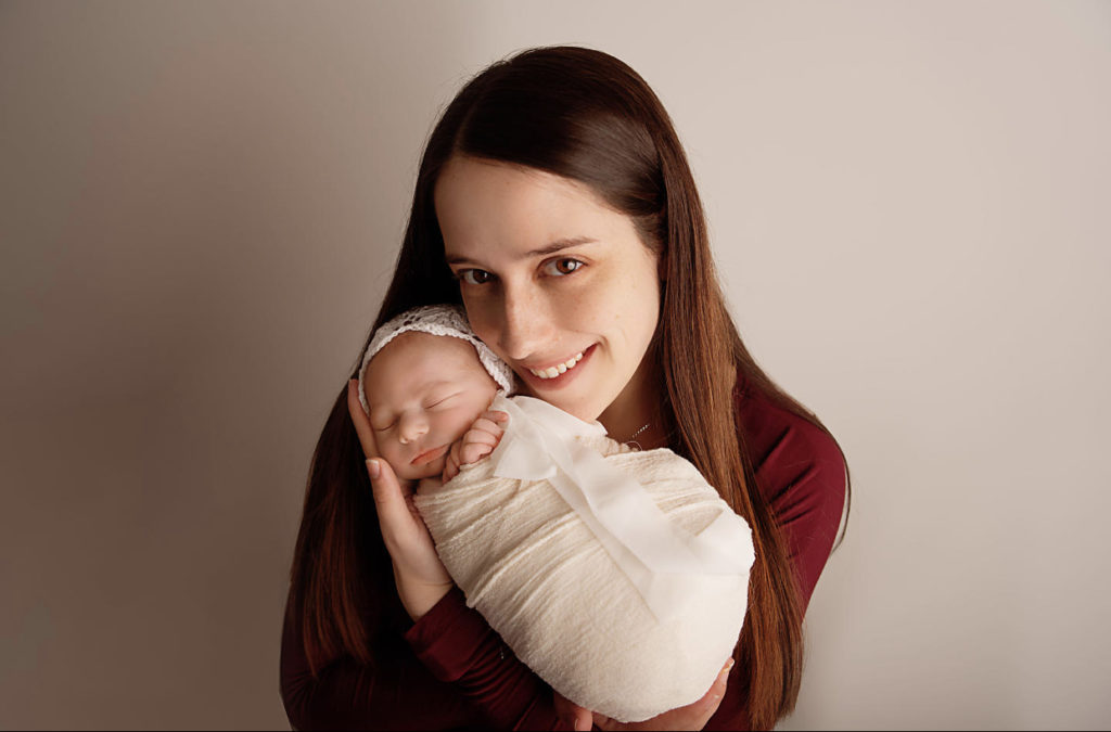 mom holding baby wearing solid burgundy long sleeved shirt what to wear for newborn session