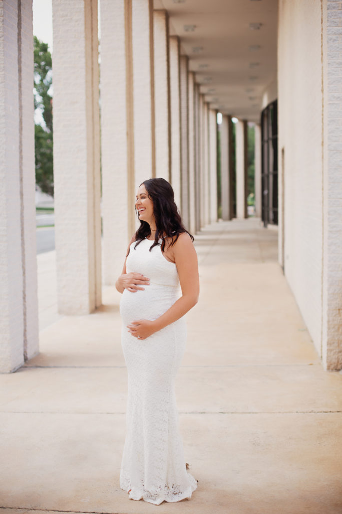 pregnant mom looking over shoulder holding belly uptown maternity photoshoot