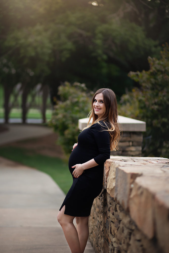pregnant woman leaning against stone bridge black casual dress what to wear for maternity photos