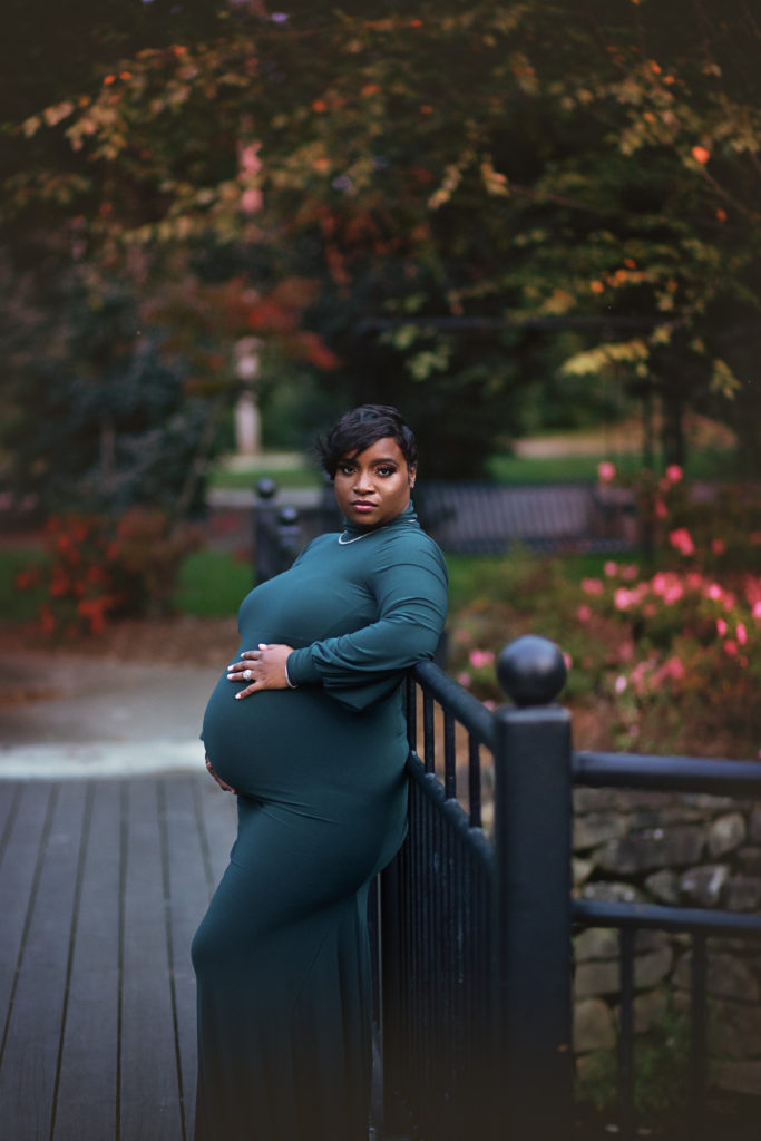 pregnant woman wrought iron bridge green dress holding belly glencairn garden maternity session