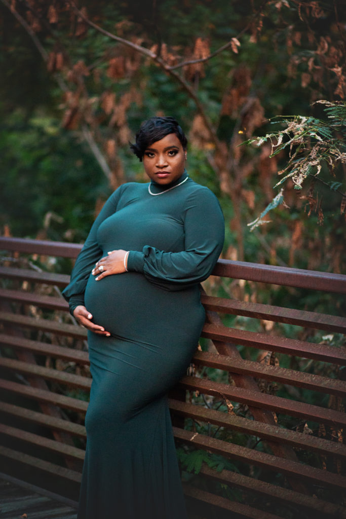 pregnant woman leaning on bridge green dress glencairn garden maternity session