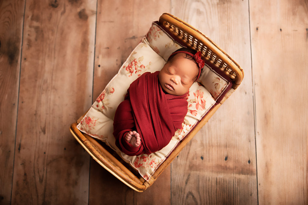 newborn baby girl on burgundy floral mattress