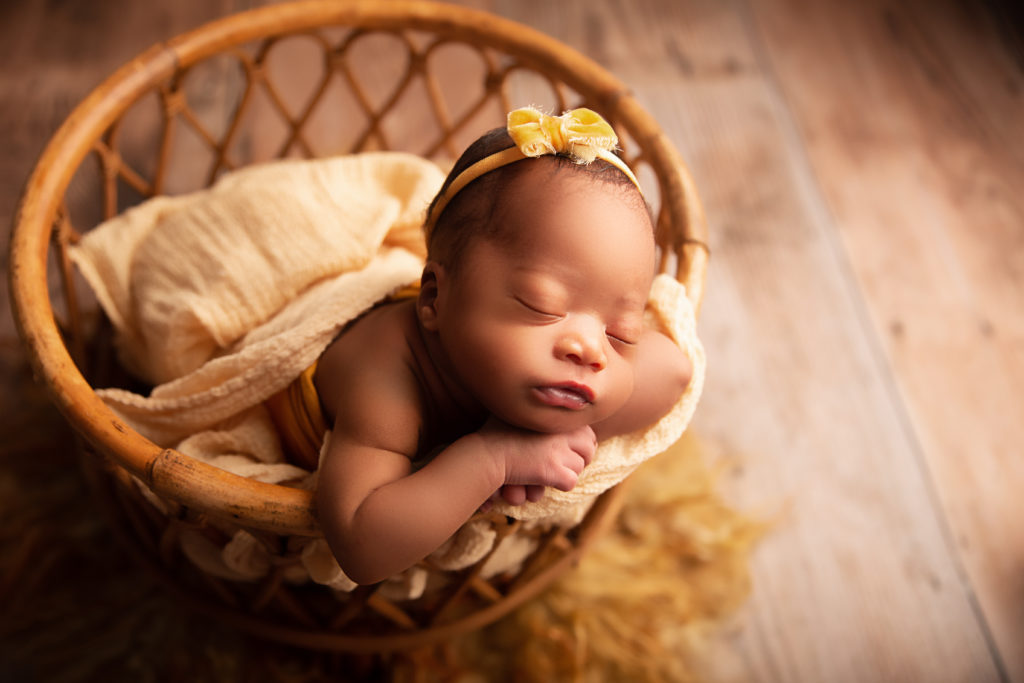 newborn girl in bamboo basket yellow hairbow